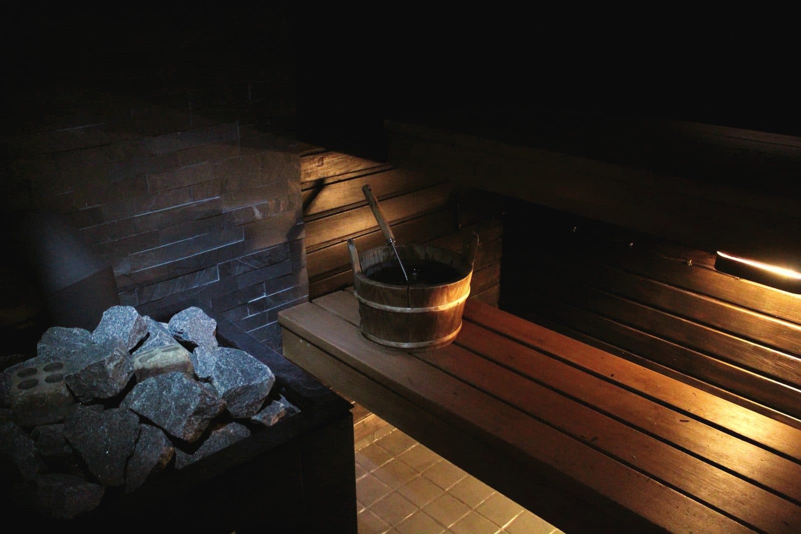 Sauna stones with a wooden bucket and ladle in a dim interior